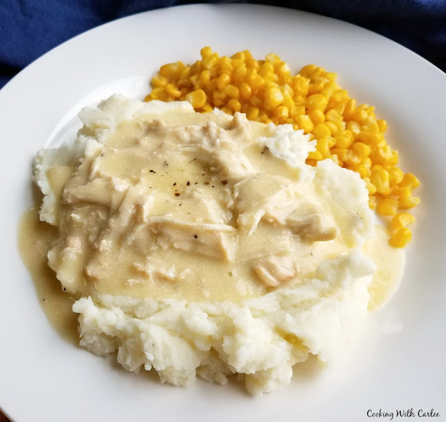 Creamy chicken and gravy in the slow cooker is like making a plate of diner comfort food at home. It is so easy to make and will make you feel are warm and full inside! plate with cream chicken on top of mashed potatoes with corn on the side