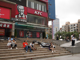 people sitting next to typhoon debris in front of a KFC in Zhuhai