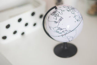 Stock photograph of a black and white globe on a white desk. The globe is turned so that the Atlantic Ocean is clearly visible, with the edge of Europe and North Africa appearing across the upper edge.