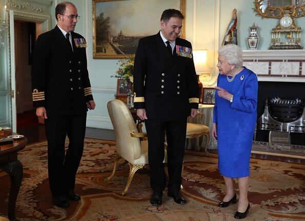 Queen Elizabeth received the outgoing and incoming Commanding Officers of HMS Queen Elizabeth. blue dress and diamond brooch