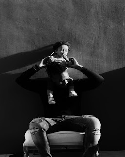 Dad with Daughter Dad holding daughter above his head while sitting in a chair.