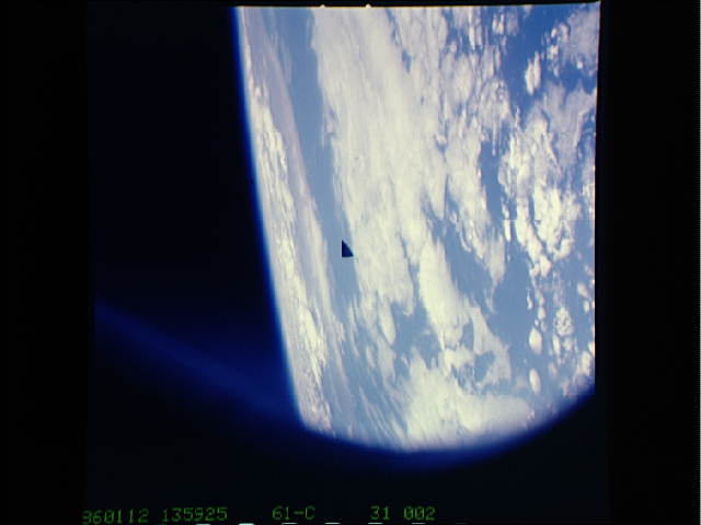 Triangle UFO between the Shuttle and the Earth is apparently an insulation tile.
