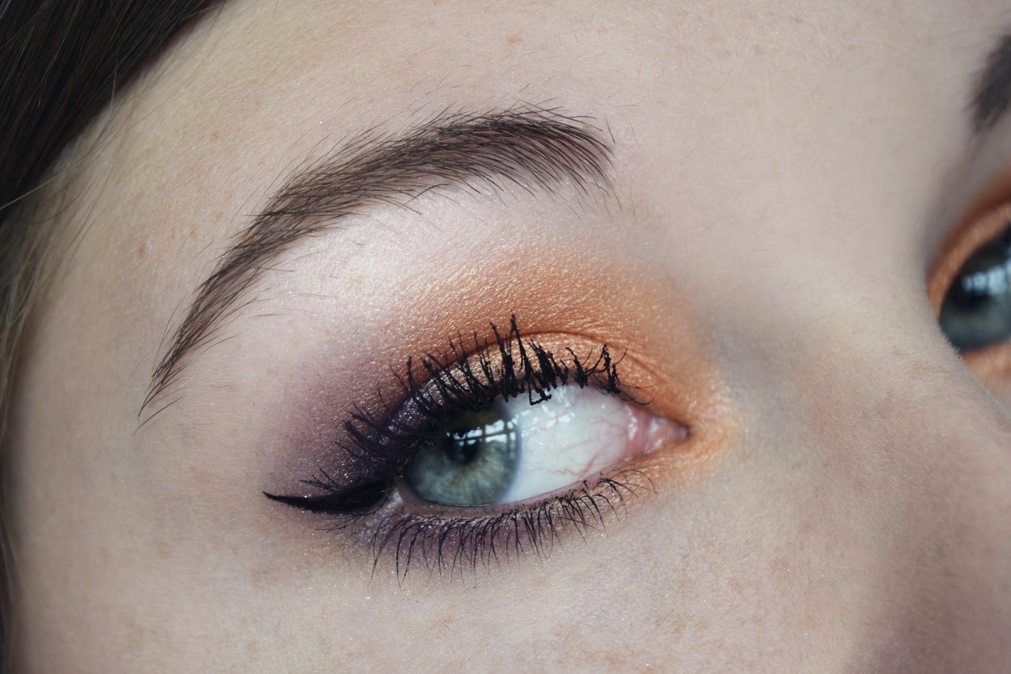 a close up shot of an eye with vivid orange and purple eyeshadow.