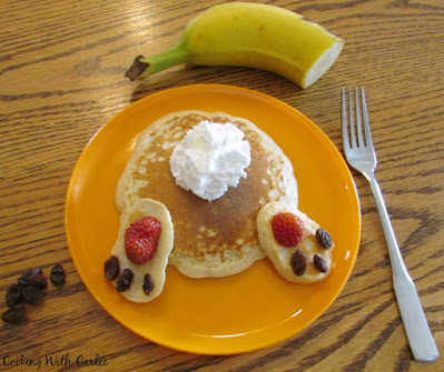 These bunny butt pancakes are cute as can be and they come together so quickly. What a great way to treat your family on Easter morning! bunny butt pancake on orange plate with banana and additional raisins