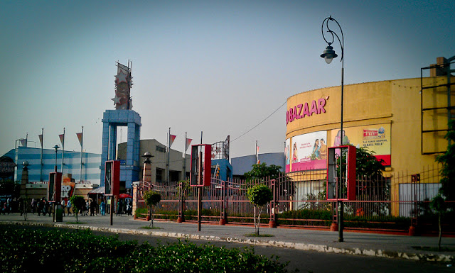 Mobile-Giri at Metro Walk, Adventure Island and Amusement Park @ Rohini, North West Delhi, - An Open Air Mall : Metro Walk Mall is actually located in Rohini area of  West Delhi which is a retail and entertainment complex as part of Entertainment City, an international standard amusement park. This integrated mix-use destination is spanning over 62 acres with Retail-Mall (Metro Walk) spread across 2.21 lakh sq. ft., i.e. one among the largest retail development in India. It is a world-class integrated destination with multiple theme park, cinemas, shops and restaurants! And it's different from other malls in Delhi and I call it Open Air Mall !!! It's not closed and various parts of Metro-Walk are spread around and people are actually walking outside of any concrete building when not in any of the showroom or Restaurant...This is first view of Metro Walk Mall from parking... It has huge parking space and charges are 30 Rs. and I don't remember if there is any time limit there !!!This mall is just opposite to apanese Park... This area of Rohini has three major land blocks,  one if covered by Japanese Park other my Metro-Walk Mall and third part is open as of now.. This is used by localites to learn car driving :)The pavement in this photograph leads to main entrance for Metro-Walk Mall from open parking !!!This retail development has both a fun / amusement / impulse driven retail mix as well as convenience shopping options...Adventure Island is one of the preferred destinations to celebrate organisational achievements and do group level activities. I read somewhere that park has been designed in a manner that every individual realizes that they share the same organisational goal...There are total 78 retail shops including eating joints. You will find many of the major brands here...Food and Beverage Outlets : KFC, Punjabi by Nature, Fast Trax, Spoon the Food Court, Pizza Hut, Yo China, Nirula's, Pind Balluchi, Flaming Wok, Gola Sizzler, Baskin Robins, Ruby Tuesday, Barista, Costa Coffe, McDonald's, Cafe Coffee Da, Geoffrey's and more..............It overlooks a large lake which acts as the separator between the Metro-Walk mall building and the amusement park. It also has a small area ( 3.5 acres) dedicated to POGO branding. Metrowalk and Adventure Island, a world class amusement park and a water park.It overlooks a large lake which acts as the separator between the Metro-Walk mall building and the amusement park. It also has a small area ( 3.5 acres) dedicated to POGO branding. Metrowalk and Adventure Island, a world class amusement park and a water park.There is some seating area constructed in terms of stairs.. and couples love to sit in front of this lake !!!Metro Walk Mall is not like other malls where all the showrooms, restaurants are available under one roof.. Its spread over te area and having various buildings... Each block connected with each other through stairs, bridges or pavements.. There is enough green areas around it and one likes walking around, that's why Walk in Metro aka Metro walk :)Retail Outlts includes : Biba, Adidas, Levis, Reebok, Pantaloon and many more.... There are lot of options for shopping lovers, children and of course boys can also eat & buy something :)This whole thing is the result of 50% partnership between Unitech and International Amusement Ltd., the promoters of Appu Ghar. People are coming from South Delhi and Gurgaon too even though it's located in West Delhi & Near North Delhi.he amusement park contains about 26 rides and attractions. All the rides here are imported from the suppliers who supply to international amusement parks like Disneyworld, Universal and Six Flags. The water park offers many rides there... Rides like Cyclone, Bush Buggies, Flip Out, Space Jump, Fire Brigade, Wild Wheels, Z Force, Sidewinder, Derby Devils, Sky Riders, Lighing Bold, Twister, Splash Dunk, Air Bus, Float Boat, Rockin Tug, Trail Train, Bumper Cars etc...There are some water fountains at ground level of this Mall and kids like to go inside these and have some bath.. Some parents don't like andothers enjoy !!! Adventure Island offers a host of special packages for schools and other educational institutions a Fun Filled Trip at the park... Not sure how good those packages are..Also there are some Family passes...which provide unlimited access to the world of 