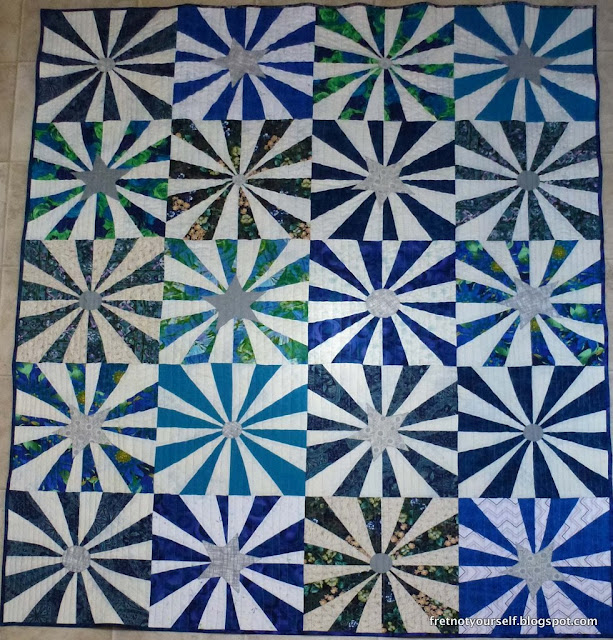 Cowboy Fireworks quilt made of blue and white pinwheel blocks with grey star centers