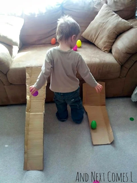 J trying to race wobbly Easter eggs on two cardboard ramps from And Next Comes L