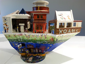 Miniature wooden painted artist's arks on display in a gallery.