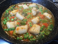 Cociendo con caldo la sepia y los guisantes Cociendo el caldo de pescado con el sofrito, la sepia, el pimiento verde y los guisantes