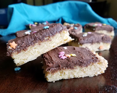 Super soft sugar cookie bars topped with super chocolaty sweetened condensed milk buttercream are a fun, easy and popular treat! close up of chocolate frosted soft sugar cookie bars