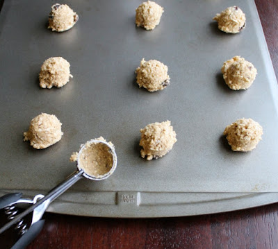scoops of oatmeal raisin cookie dough on a cookie sheet ready to bake