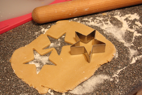 sugar cookie dough with a star cookie cutter, and some stars cut out of the rolled out dough