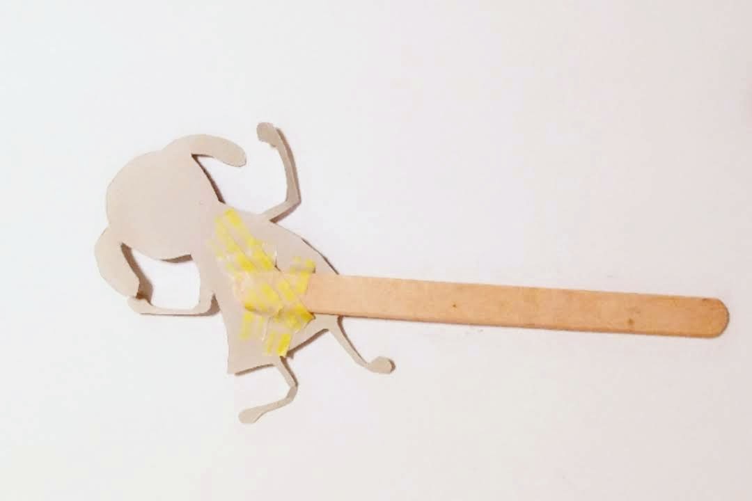 Attaching the child figurine to the craft stick.