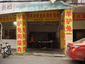 butcher shop with signs indicating it sells goat, donkey, rabbit, dog, and cat meat