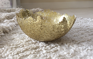 a DIY homemade gold glitter bowl sitting on a soft white blanket