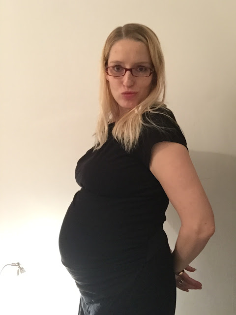 A side view of me at 36 weeks pregnant pulling a pouting face