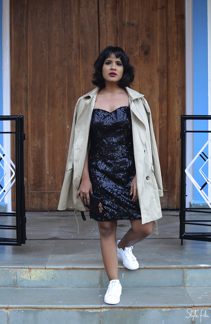 Image of woman wearing winter fashion clothing with a Zara beige trench coat, H&M black sequin dress and white Adidas Originals Stan Smith sneakers with red lipstick, burgundy nail polish and wavy bob hairstyle