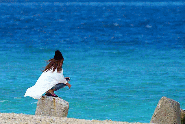 woman, white shirt, black cap, near sea