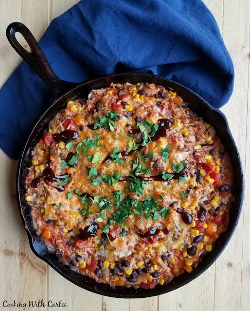 One pan BBQ pulled pork and rice skillet dinner is full of flavor and texture. It will have everyone coming back for a little more and leave you with very few dishes too! cast iron skillet filled with bbq pulled pork and rice skillet supper