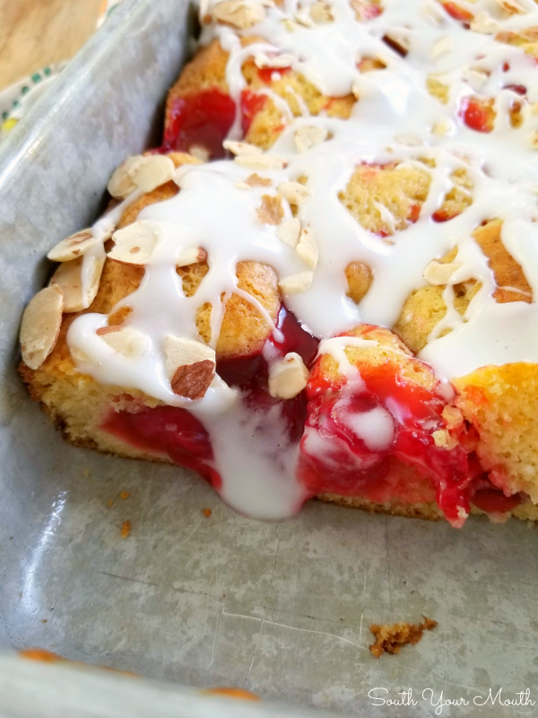 Cherry Danish Cake | An easy semi-homemade cake recipe dotted with cherry pie filling, drizzled with sour cream icing and topped with slivered almonds.