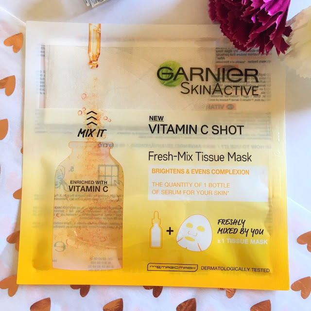Garnier Fresh-Mix Tissue Mask - Vitamin C Shot in the centre of the photo. Flowers to the right hand side in the corner