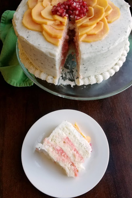 Soft white cake filled with blood orange curd and wrapped in dragonfruit buttercream. This stunning cake is a tropical fruit dream come true! first slice of cake served on small plate with remaining cake on glass pedestal