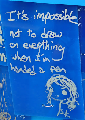 Graffiti--"It's impossible not to draw on everything when I'm handed a pen" and a drawing of a girl. Silver ink on royal blue background.