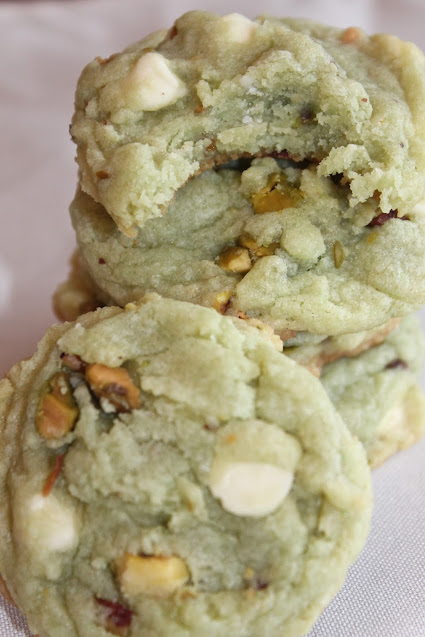 Finished white chocolate pistachio pudding cookie with one with a bite out of it.