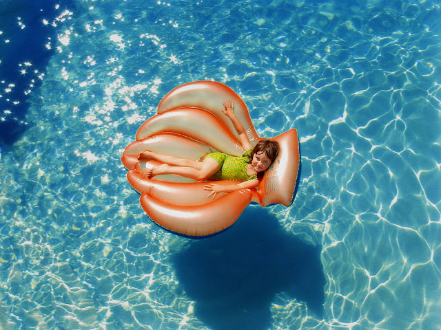 Pool Floating A child laid on an orange float in a pool.