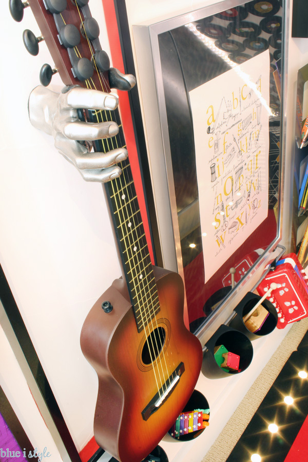 This silver hand guitar holder makes a big statement on this music gallery wall.