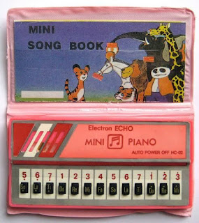 Pequeno piano que era capaz de reproduzir canções variadas. Sucesso da infância nos anos 80 e 90.