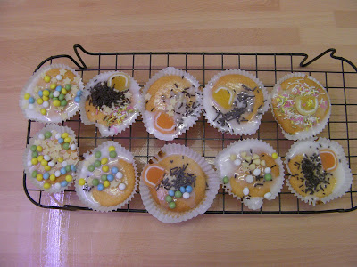 homemade fairy cakes with decorations on wire drying rack