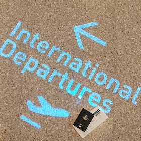 Floor sIgn for international departures, with a passport and boarding pass next to it.