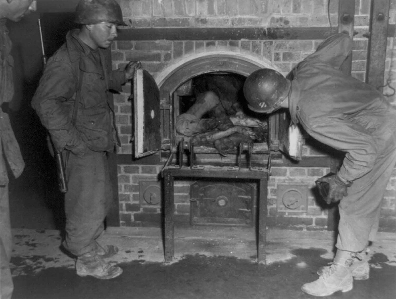 Three U.S. soldiers look at bodies stuffed into an oven in a crematorium in April of 1945. Photo taken in an unidentified concentration camp in Germany, at time of liberation by U.S. Army.