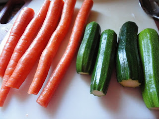 5 carrots and 4 zucchini with ends cut off on a cutting board.