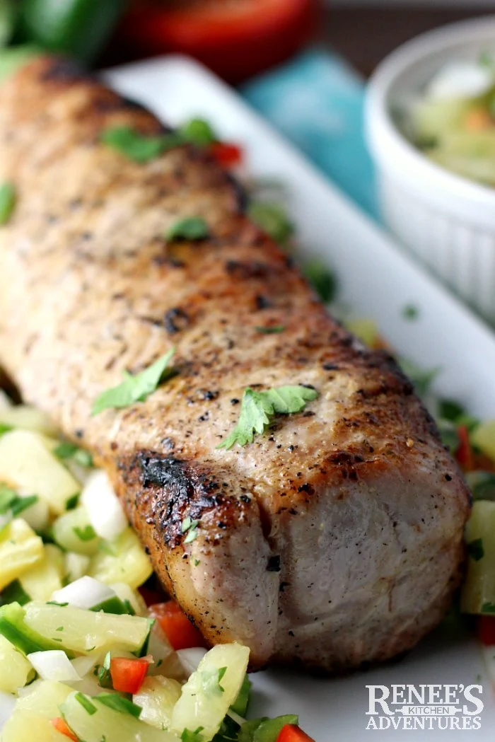 Close up of Grilled Pork Loin with Pineapple Salsa by Renee's Kitchen Adventures on a white platter, ready to serve