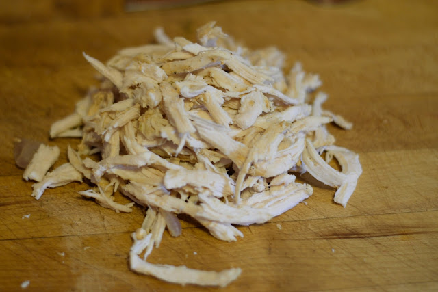 The chicken shredded on the cutting board. 