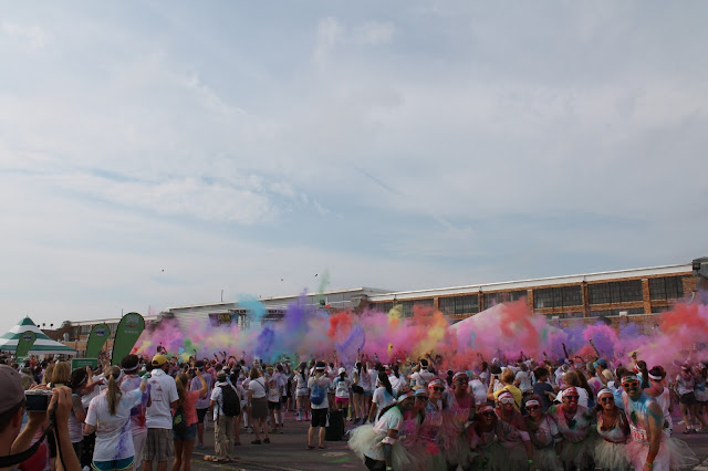 A group of people at a color run throwing colored powder into the air 