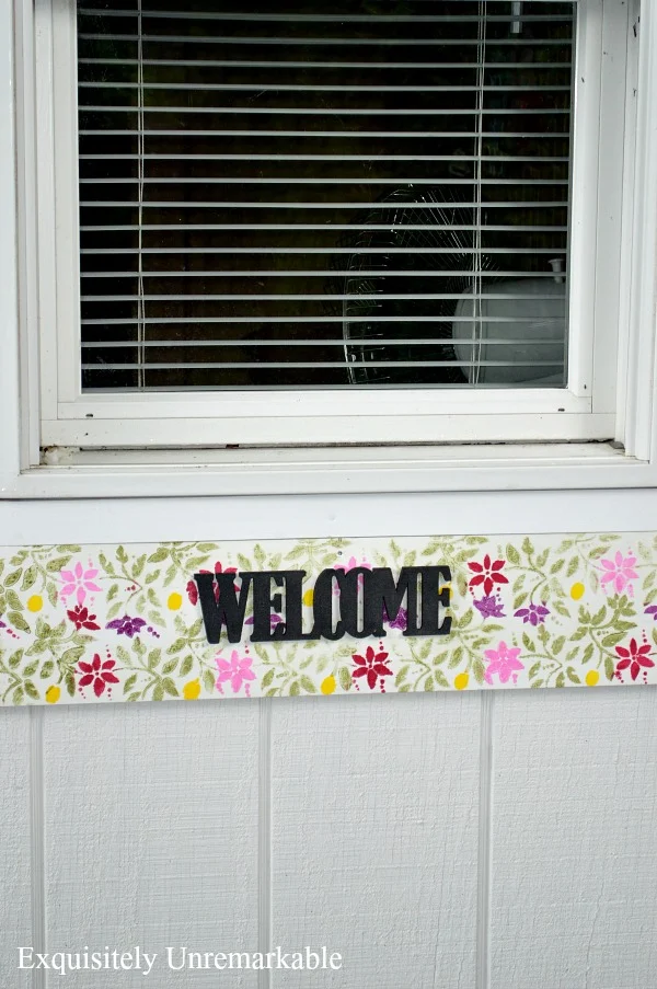 Floral Welcome Stenciled Sign nailed to white pool cabana under window