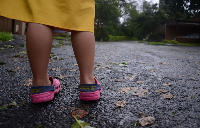 Kecil outside in her pink shoes and raincoat