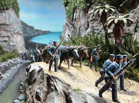 Diorama of 19th-century soldiers walking along a track near the sea.