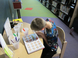 a person looks at a book of illustrations from Captain Underpants and works on making an illustration himself to put on a button