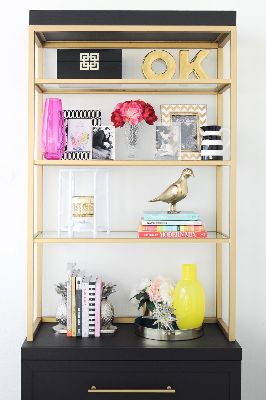 Black and gold etagere or bookcase decorated and styled with spring colors and floral accents. Black and gold etagere or bookcase decorated and styled with spring colors and floral accents.