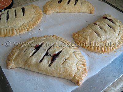 A photo of four cherry hand pies resting on parchment paper.