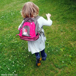 Kleinkind rennt über Wiese mit Rucksack Mädchen Die besten Mama-Hacks für die erste Kita- und Kindergartenzeit