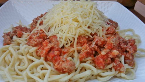 Una pasta casera con carne de cordero, tomate y queso rallado
