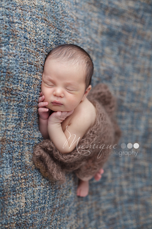 Sleeping infant on textured blanket covered by a lacy knit scarf