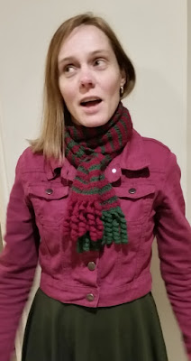 A silly photo of Jodie wearing the scarf in a layered knot over a purple-pink cotton jacket and dark green dress. Jodie's eyes are looking to the left and sightly upwards as her mouth is open. Her straight hair hangs over the front of her shoulder on the left hand side and it managed to get tucked into the scarf on the right hand side.