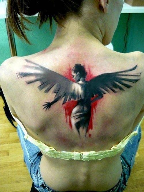 Chica joven sentada de espaldas lleva coleta y va en jeans, tiene el tatuaje de un angel en la espalda
