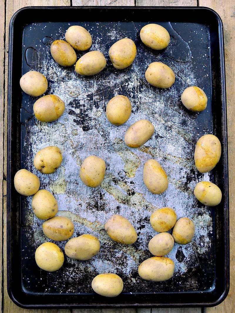 Baby Yukon gold potatoes on a metal sheet pan drizzled with olive oil.